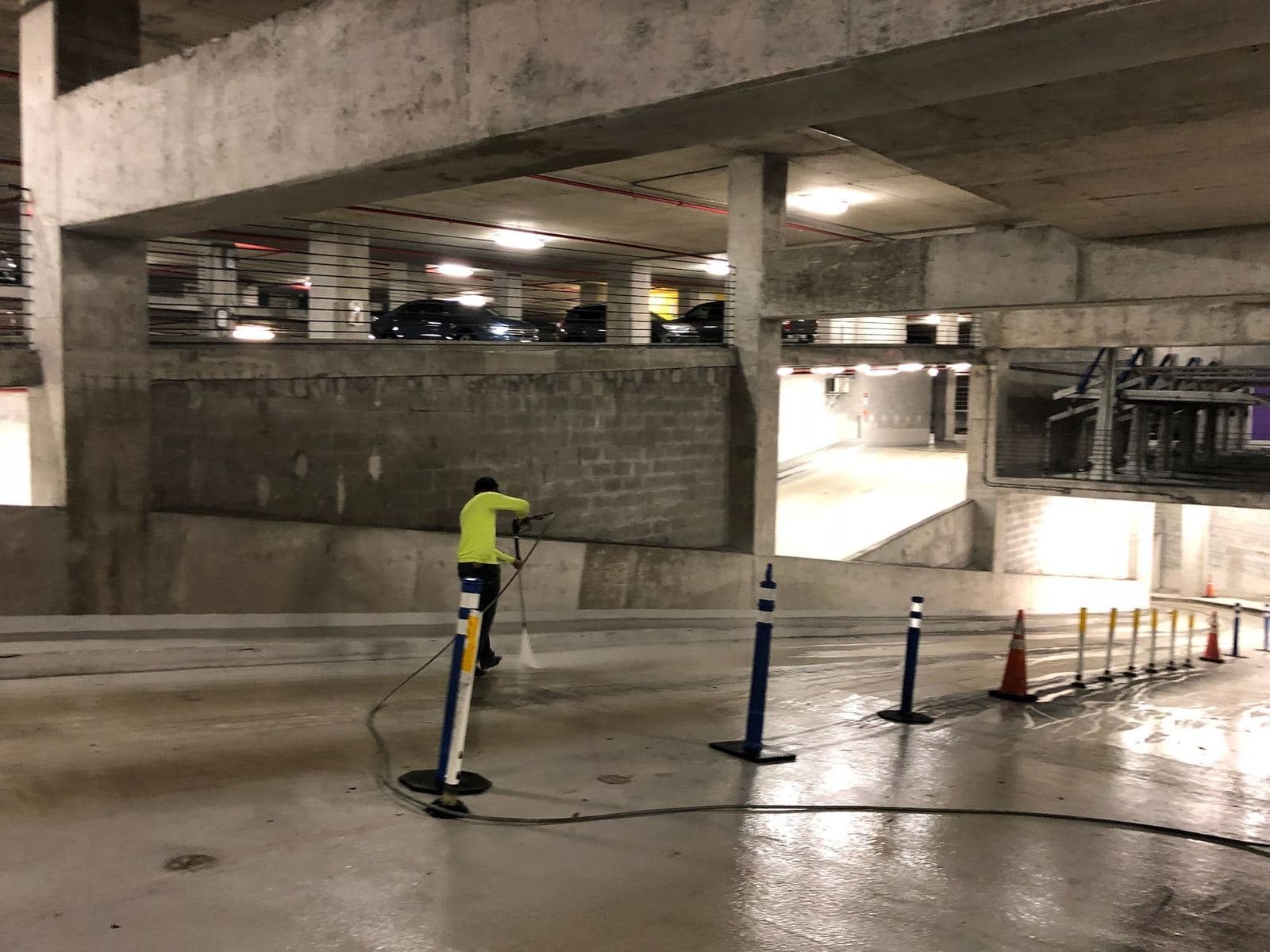 Crew pressure washing a parking garage with safety cones — Finesse Cleaning, South Florida