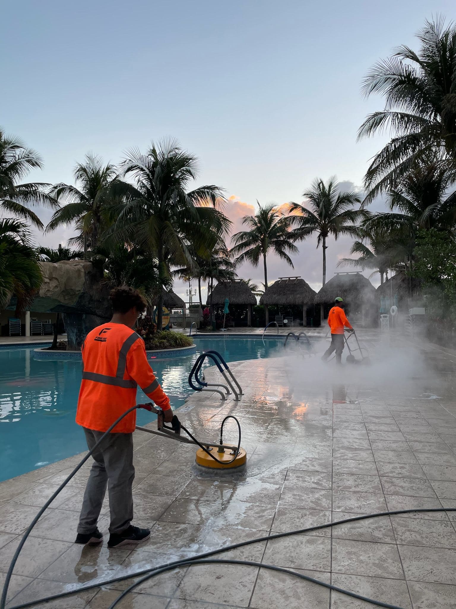 Crew pressure washing a pool deck at dusk — Finesse Cleaning, South Florida