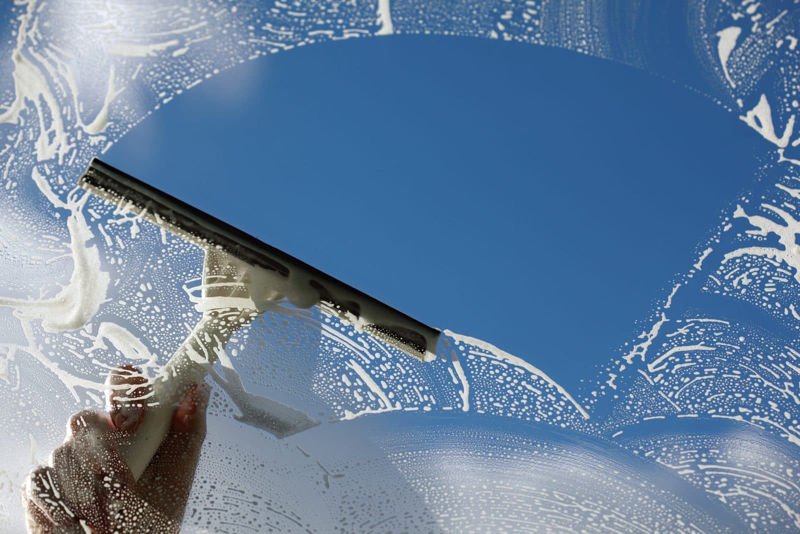 Close-up of a squeegee clearing soap from a window — Finesse Cleaning, South Florida